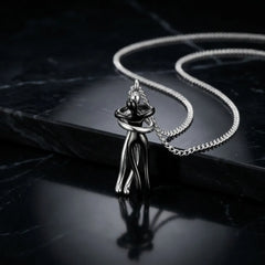 A silver-toned metal pendant necklace featuring an abstract, stylized human figure holding a heart, displayed on a black marble surface with a matching chain.