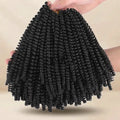 Black curly cornrow hair extensions held up by hands against a plain beige background.