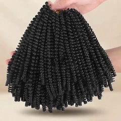 Black curly cornrow hair extensions held up by hands against a plain beige background.