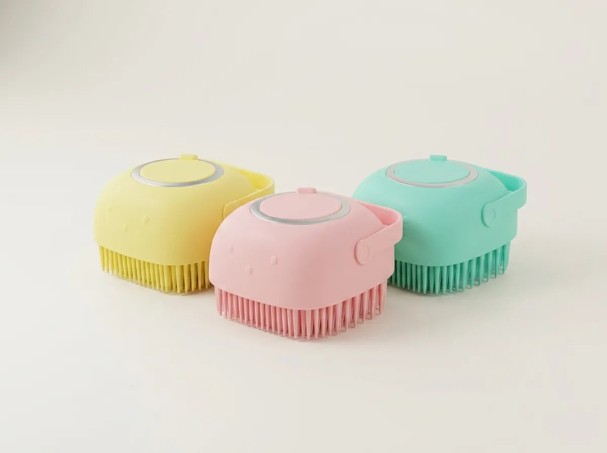Three small handheld scrubber brushes in pastel yellow, pink, and mint green, arranged on a clean off-white background.
