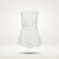 A white strapless romper with a ruffled neckline, a matching fabric tie belt at the waist, and a ruffled hem, shown floating against a light off-white background.